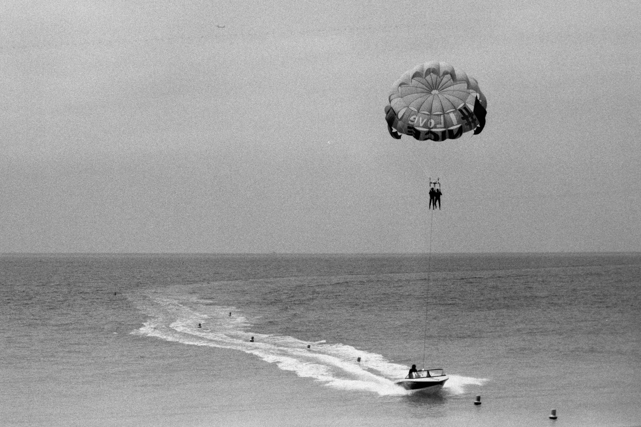 A parasail towed by a speedboat across open sea, its wake curving behind.