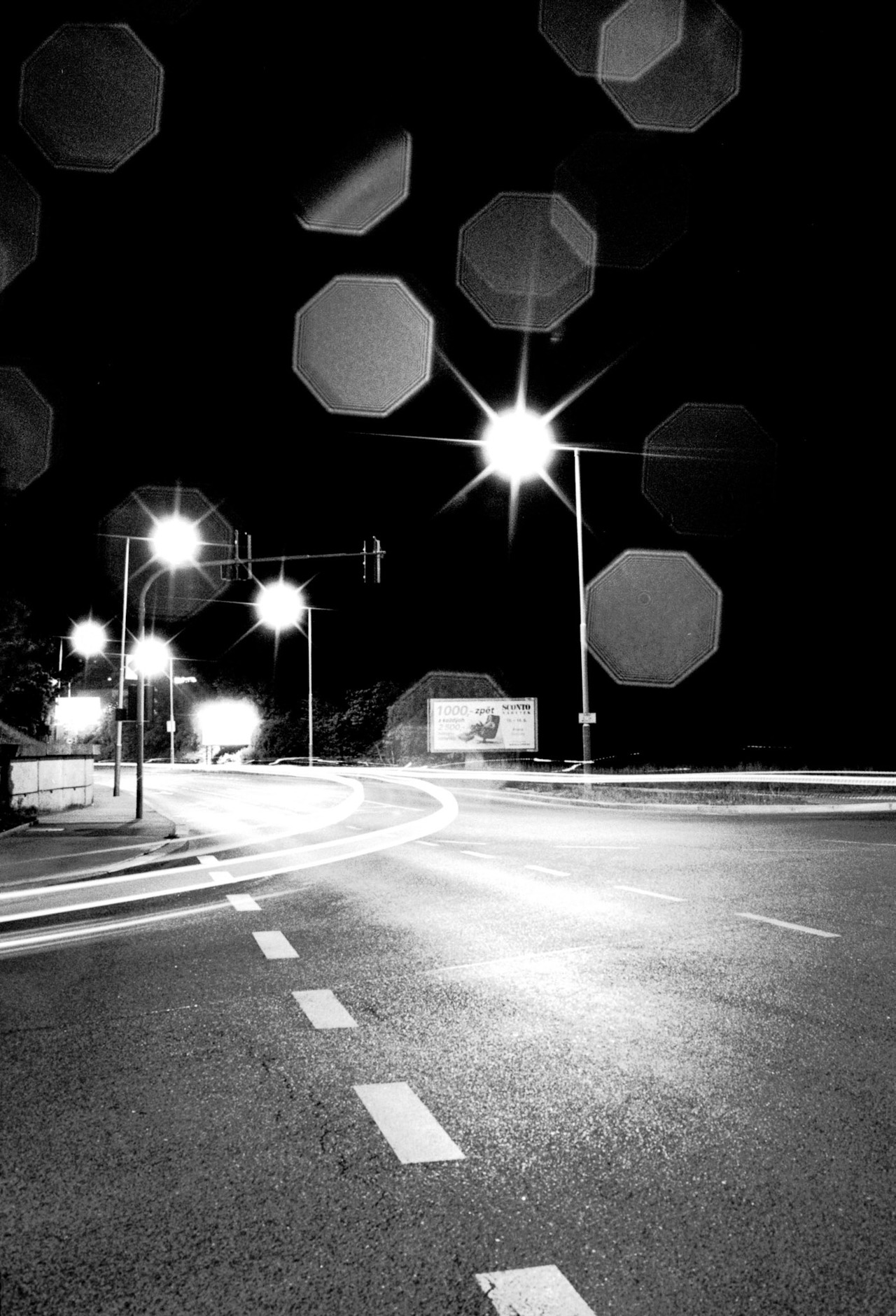 An empty road junction at night, with starburst street lights and lens flare.